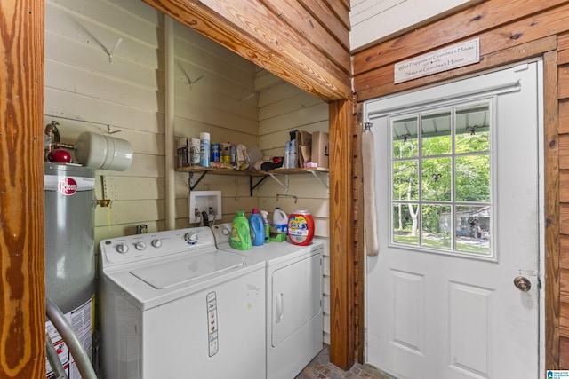 laundry room with gas water heater, wood walls, laundry area, and washer and dryer