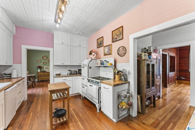 kitchen featuring white dishwasher, tasteful backsplash, wooden counters, and wooden walls