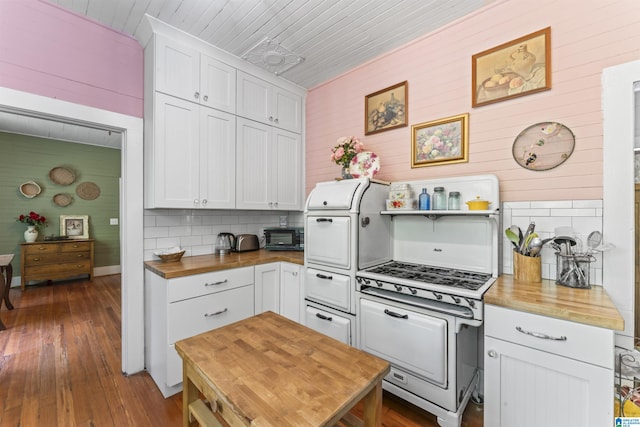 kitchen featuring backsplash, white cabinetry, white gas stove, and butcher block counters
