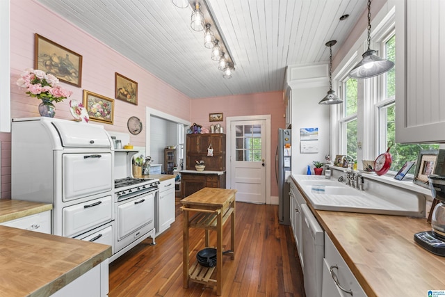kitchen with hanging light fixtures, a sink, dark wood-style floors, wood counters, and white appliances