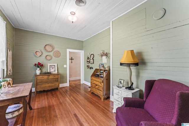 living area with wooden walls, wood ceiling, wood-type flooring, and visible vents