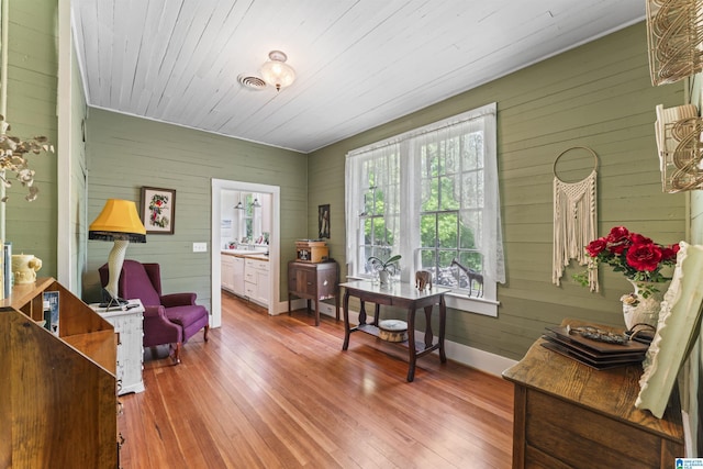office space with visible vents, baseboards, wood walls, and hardwood / wood-style flooring