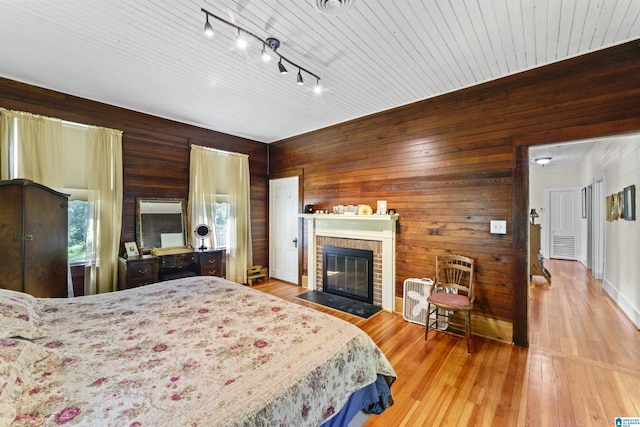 bedroom with visible vents, wood walls, wood finished floors, and a fireplace
