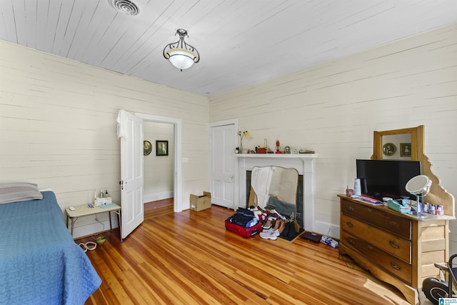 bedroom with a closet, visible vents, wood finished floors, and a fireplace