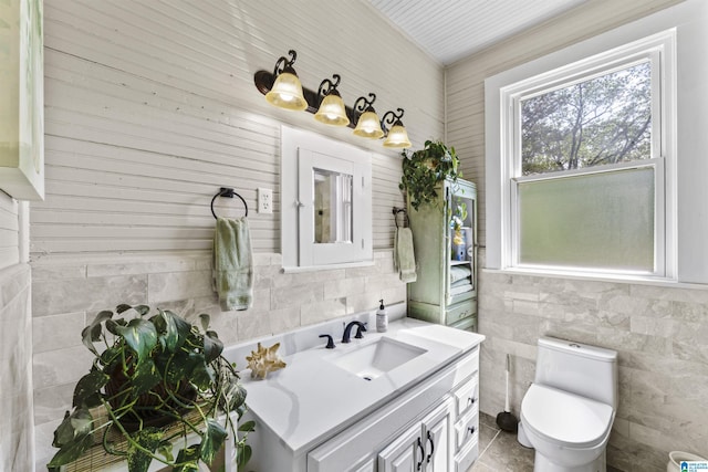 bathroom with vanity, toilet, and tile walls