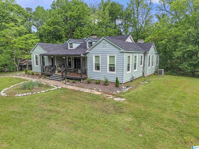 view of front of house with covered porch, a chimney, central AC, a front lawn, and a shingled roof