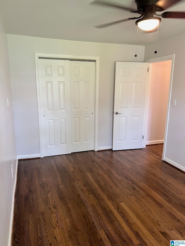 unfurnished bedroom featuring baseboards, a ceiling fan, dark wood finished floors, and a closet