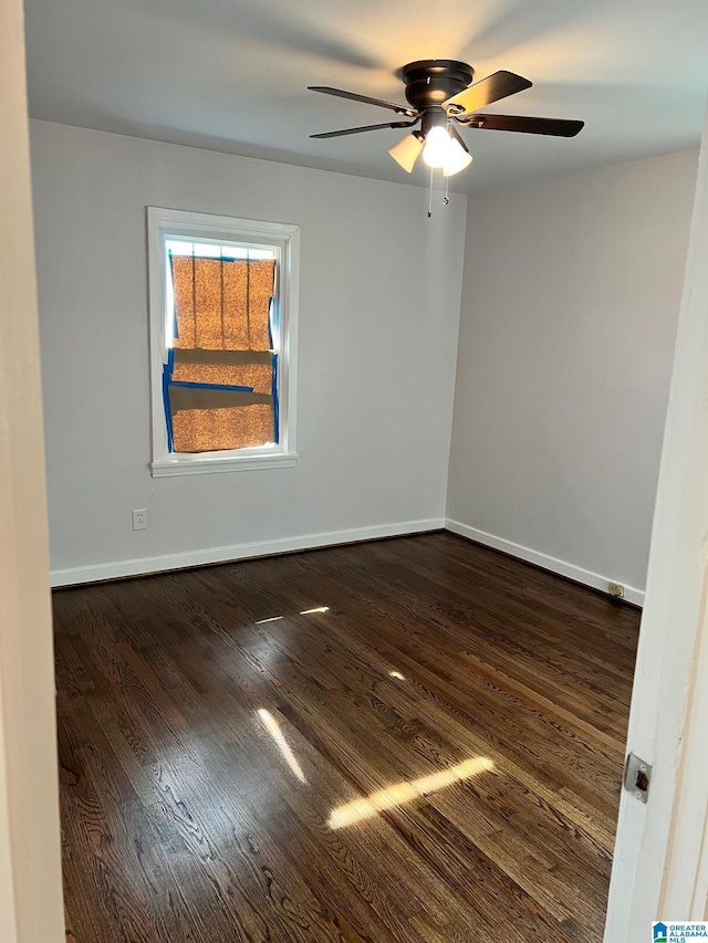 unfurnished room featuring baseboards, a ceiling fan, and dark wood-style floors