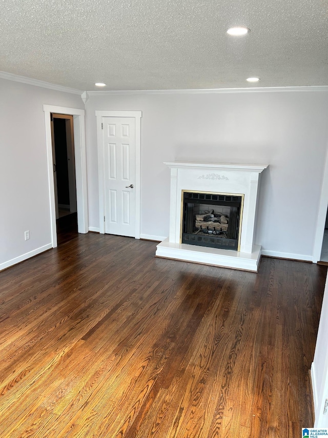 unfurnished living room featuring a textured ceiling, wood finished floors, a fireplace with raised hearth, ornamental molding, and recessed lighting