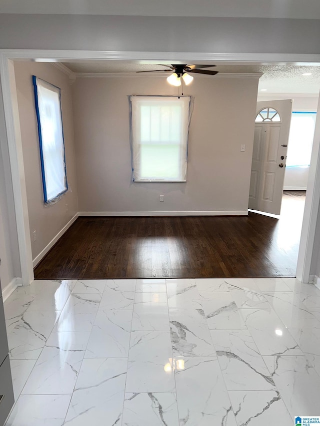 empty room featuring baseboards, ornamental molding, ceiling fan, and wood finished floors