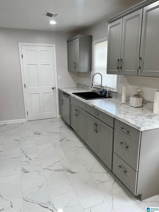 kitchen featuring gray cabinets, visible vents, stainless steel dishwasher, a sink, and marble finish floor