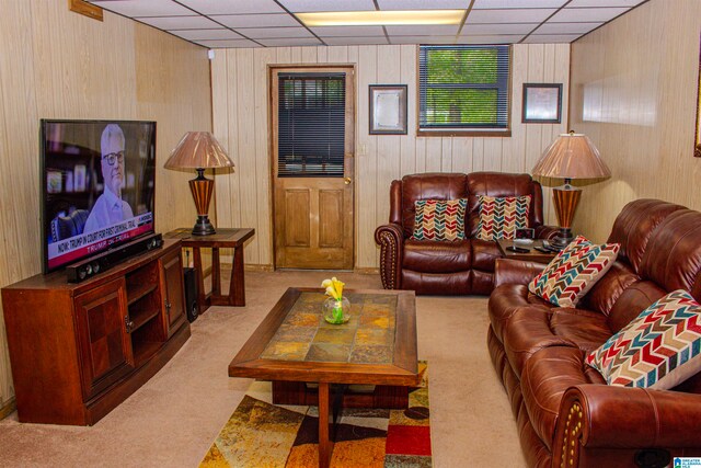 living room featuring wooden walls, carpet flooring, and a paneled ceiling