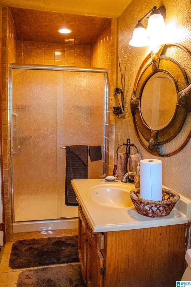 bathroom featuring vanity, wallpapered walls, and a shower stall