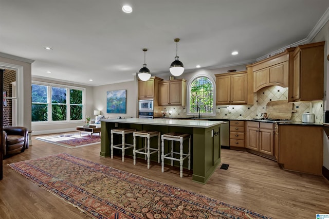 kitchen featuring ornamental molding, stainless steel appliances, a center island, and plenty of natural light