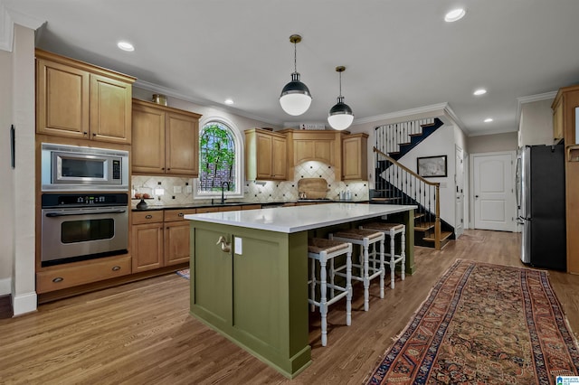 kitchen featuring a kitchen island, light wood-style floors, stainless steel appliances, and ornamental molding