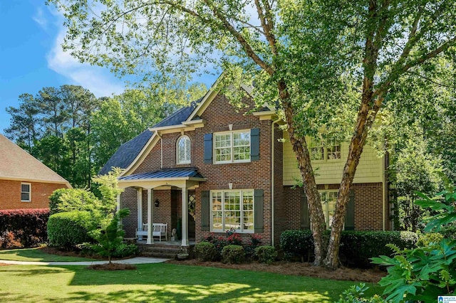 view of front of property featuring a front lawn, brick siding, and roof with shingles