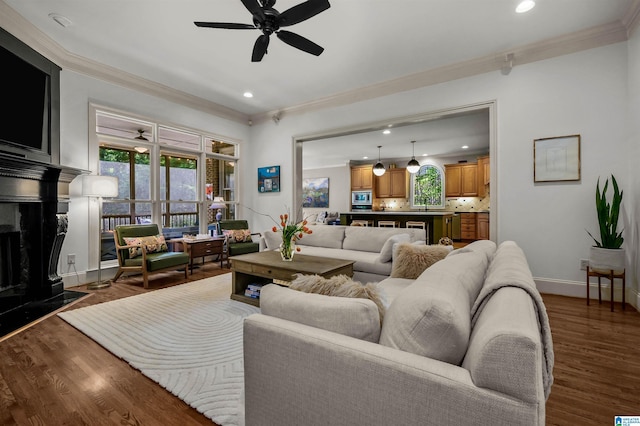 living room with a ceiling fan, ornamental molding, recessed lighting, and dark wood-type flooring