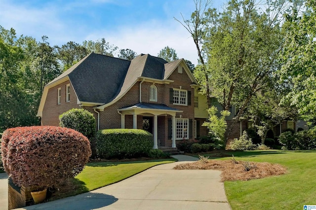craftsman-style house with a shingled roof, a front lawn, and brick siding