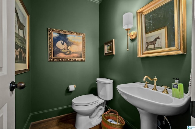 bathroom featuring toilet, baseboards, a sink, and wood finished floors