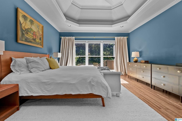 bedroom with a tray ceiling, ornamental molding, and wood finished floors
