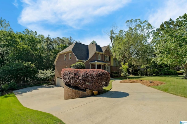 view of side of property with a garage, fence, concrete driveway, a yard, and brick siding