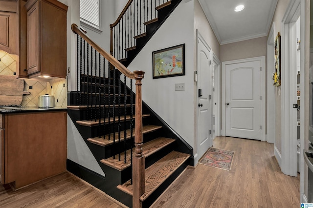 staircase featuring ornamental molding, baseboards, recessed lighting, and wood finished floors