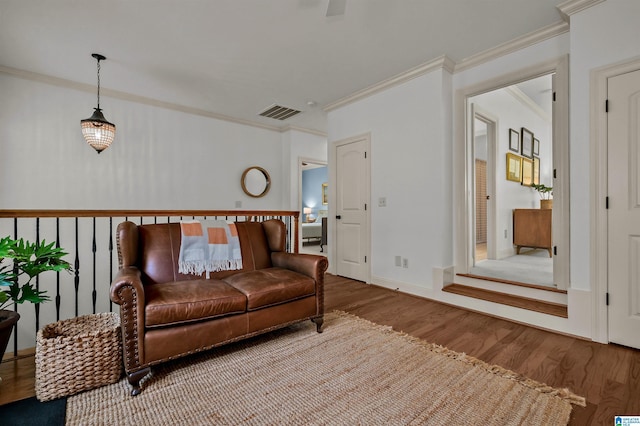 living area featuring baseboards, visible vents, crown molding, and wood finished floors