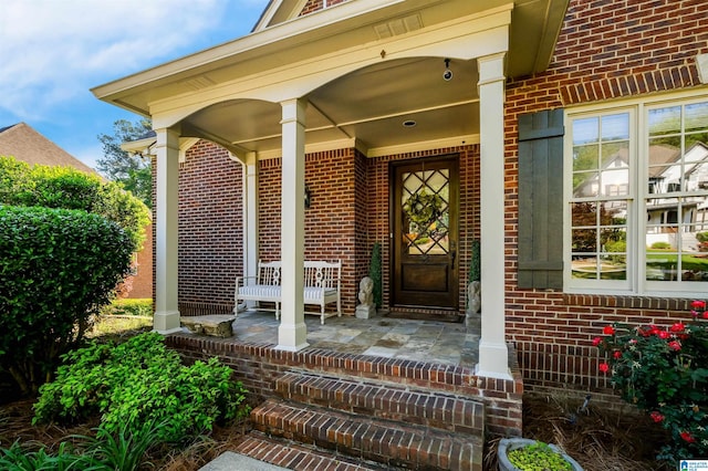 entrance to property featuring covered porch and brick siding