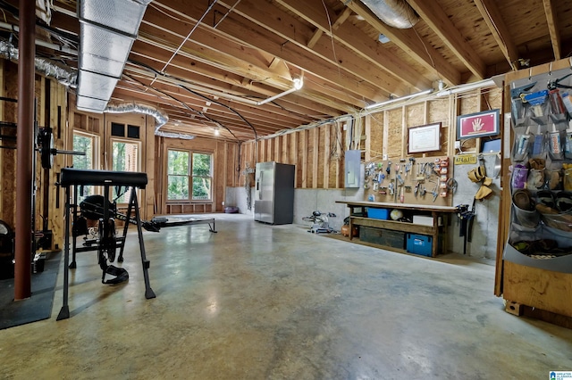 basement with electric panel, stainless steel fridge, and a workshop area