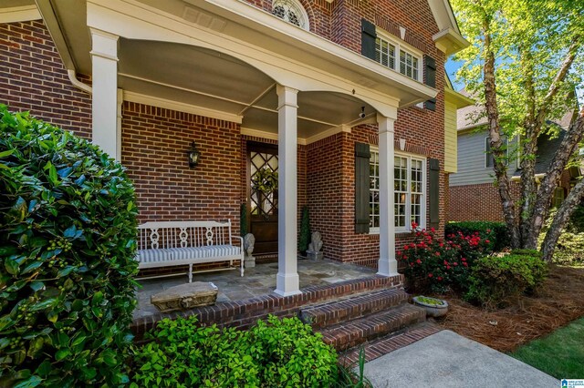 doorway to property with brick siding and covered porch