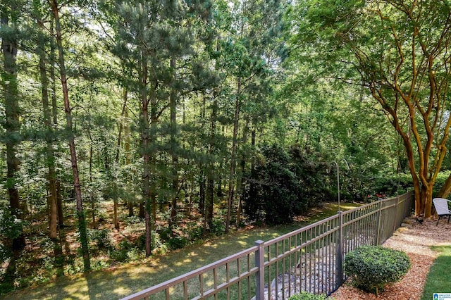 view of yard featuring a wooded view and fence