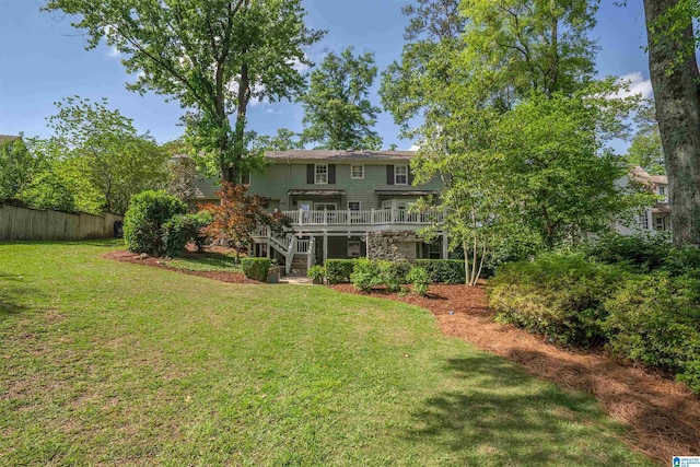 rear view of property with a lawn, stairway, a wooden deck, and fence