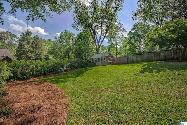 view of yard with an outbuilding, a fenced backyard, and a storage unit