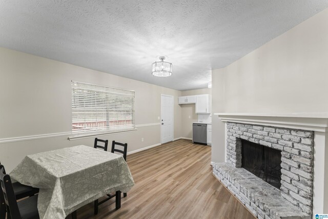 603 Danton Ln, Irondale, AL 35210 - dining area featuring a textured ceiling, a fireplace, light wood-type flooring, baseboards, and an inviting chandelier