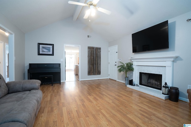 living room featuring light wood-style floors, a ceiling fan, a tile fireplace, beamed ceiling, and visible vents