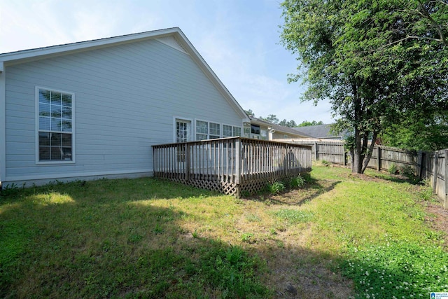 back of property with a fenced backyard, a wooden deck, and a lawn
