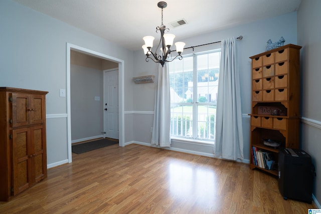unfurnished dining area with a wealth of natural light, light wood-type flooring, visible vents, and a notable chandelier