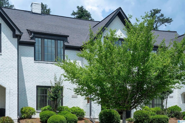 view of side of home with a high end roof and a chimney