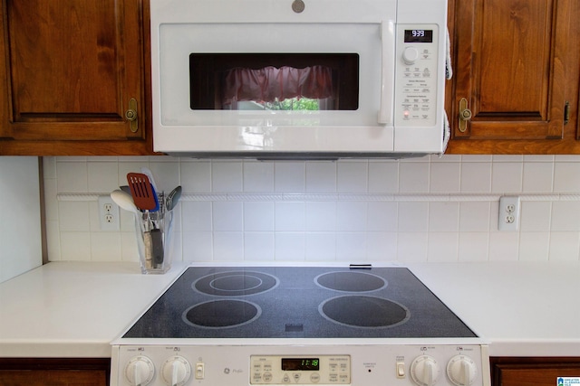 836 Tulip Poplar Dr, Hoover, AL 35244 - kitchen view of white microwave, stove, light countertops, decorative backsplash, and brown cabinets
