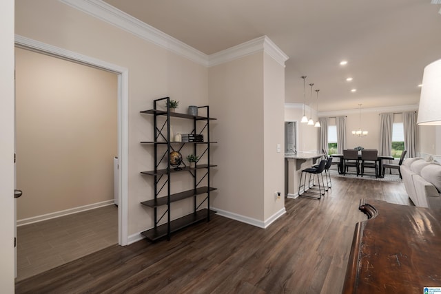 corridor featuring an inviting chandelier, ornamental molding, dark wood-style flooring, and baseboards