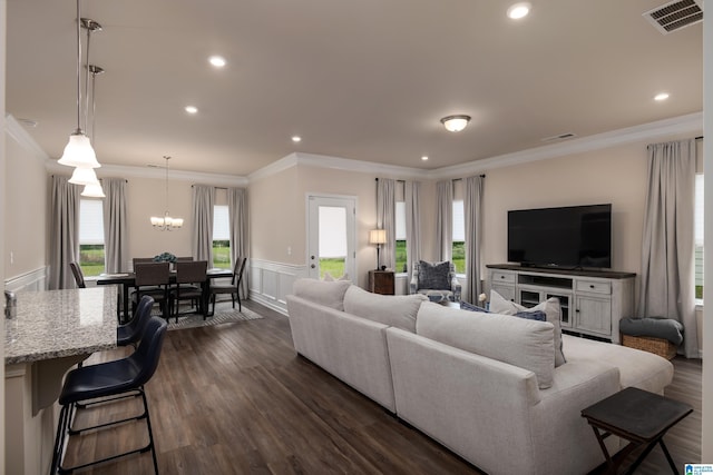 living area with visible vents, plenty of natural light, wainscoting, and crown molding