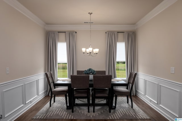 dining room featuring crown molding, dark wood-style flooring, an inviting chandelier, and a wainscoted wall