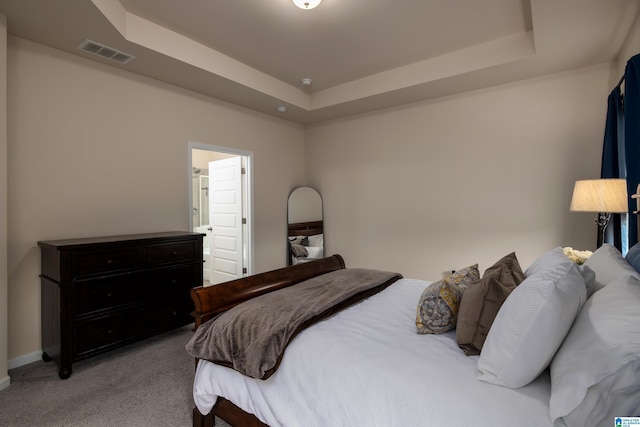 carpeted bedroom featuring baseboards, visible vents, and a raised ceiling