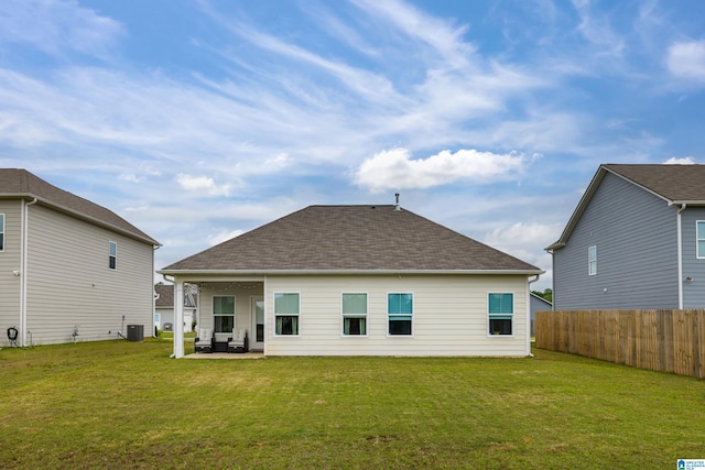 rear view of house with fence, roof with shingles, cooling unit, a patio, and a yard