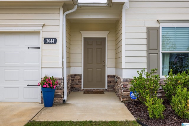 doorway to property with an attached garage and stone siding
