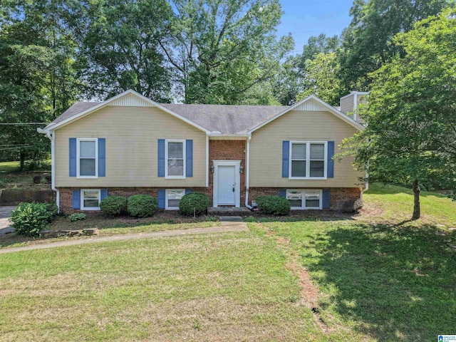 raised ranch with a chimney, a front lawn, and brick siding