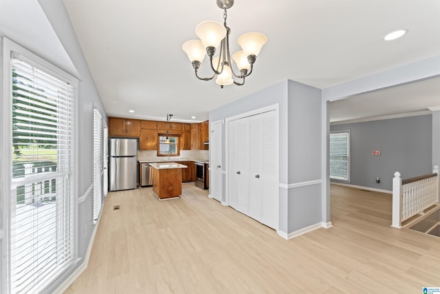 kitchen featuring a notable chandelier, appliances with stainless steel finishes, light countertops, brown cabinetry, and light wood-style flooring