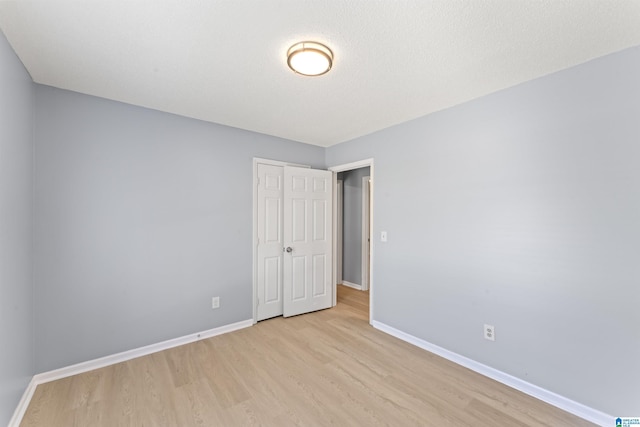 unfurnished bedroom featuring baseboards, a closet, and light wood finished floors