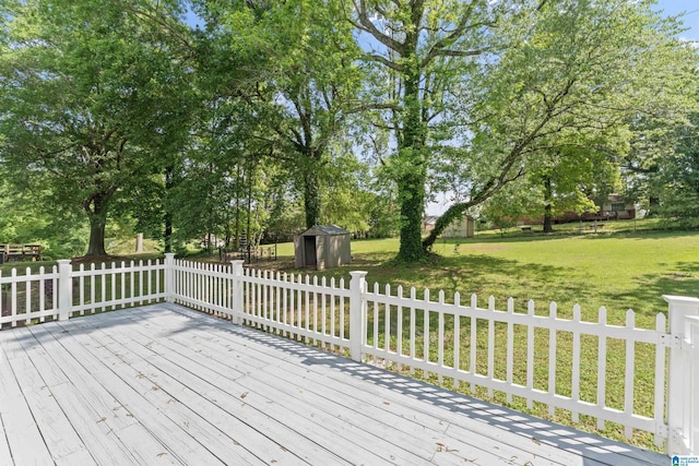 wooden deck featuring a yard, fence, an outbuilding, and a shed