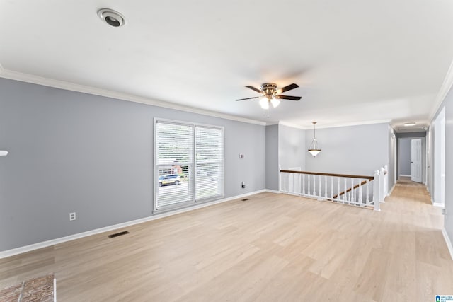 unfurnished room with light wood-style flooring, a ceiling fan, baseboards, visible vents, and ornamental molding